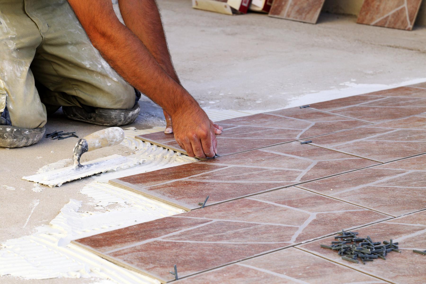 Tiler setting floor tiles in place