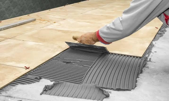 Adhesive being spread for large-format tiles